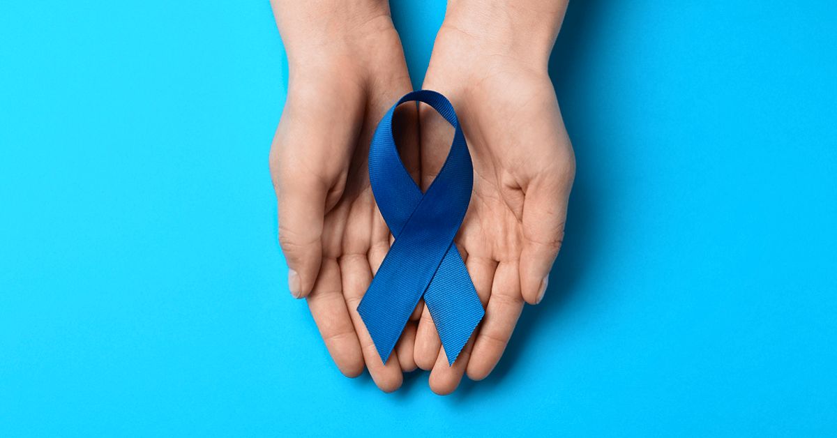 Two hands gently holding a blue awareness ribbon against a bright blue background.