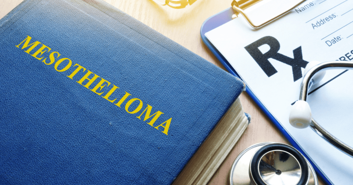 A blue book with the title "MESOTHELIOMA" in yellow letters, placed next to a medical prescription pad with "Rx" prominently displayed, and a stethoscope resting nearby on a wooden surface.